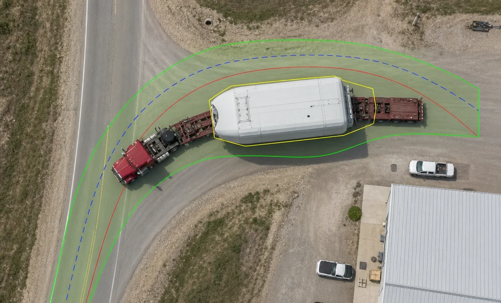 Aerial view of an articulated heavy-haul truck turning through an intersection with its swept-path envelope drawn on the road